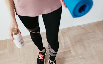 Close-up of a yoga mat and water bottle on a wooden floor.